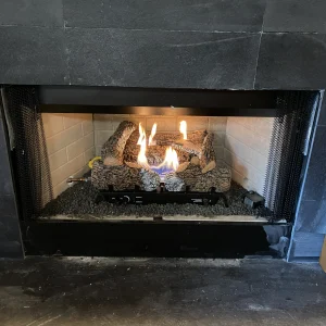 Gas fireplace in a Hampton home after repair, showing restored burner operation and realistic ceramic logs.