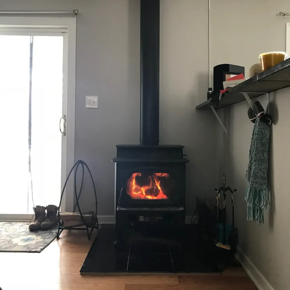 Freestanding EPA-certified wood stove in Virginia Beach home, shown in use with warm fire and professionally finished venting system.