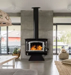 Buck Stove Model 91 freestanding catalytic wood stove in a modern open living space with large windows and concrete wall surround.
