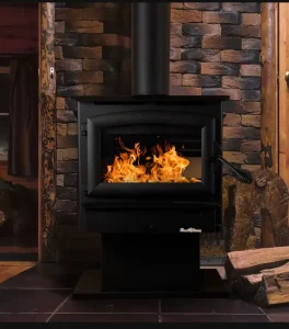 Buck Stove Model 21NC freestanding wood stove installed in a cozy cabin-style living room with stacked stone backdrop.