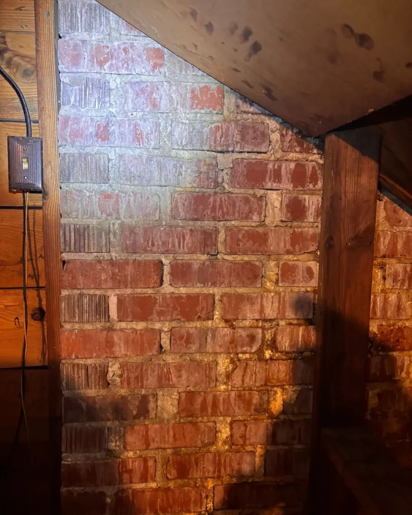 Attic brick chimney showing moisture staining and water intrusion from chimney flashing leak