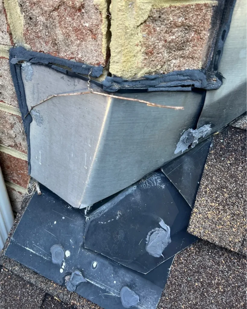 Close-up of chimney flashing leak showing excessive caulking and failed sealant at brick chimney roofline