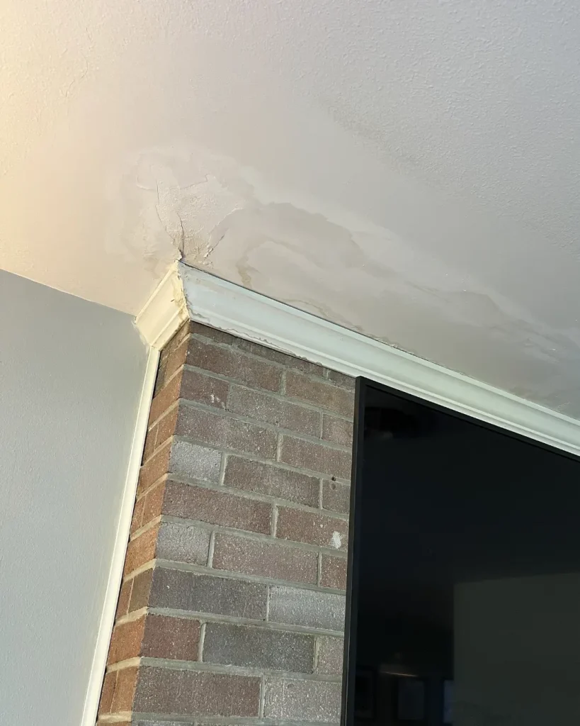 Water stains on interior wall and ceiling caused by chimney flashing leak near chimney structure