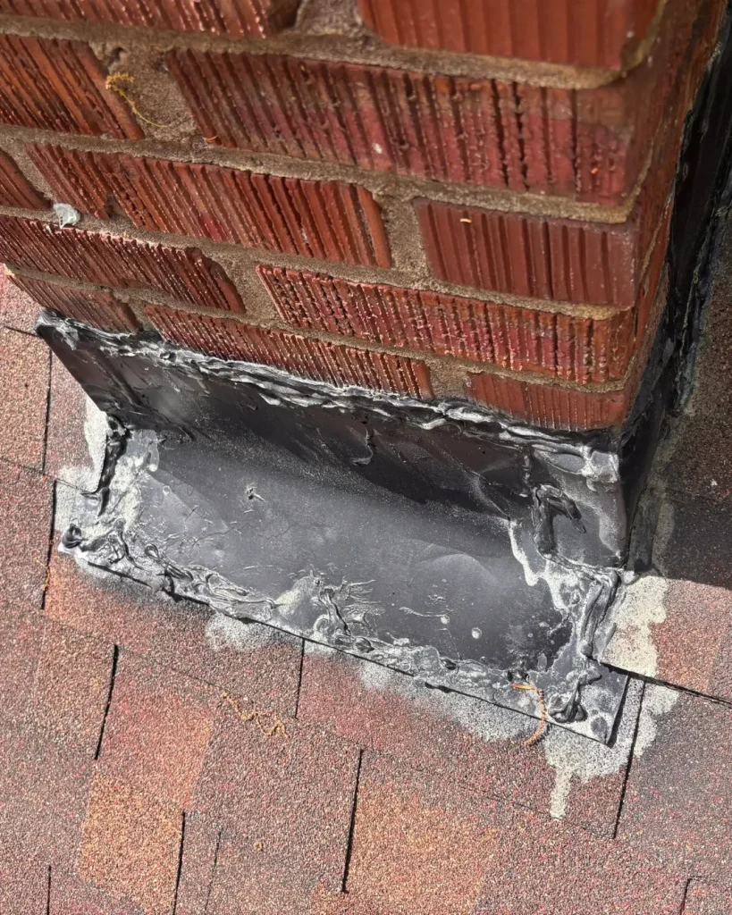 Chimney flashing leak with excessive roof sealant showing failed temporary repair at chimney base