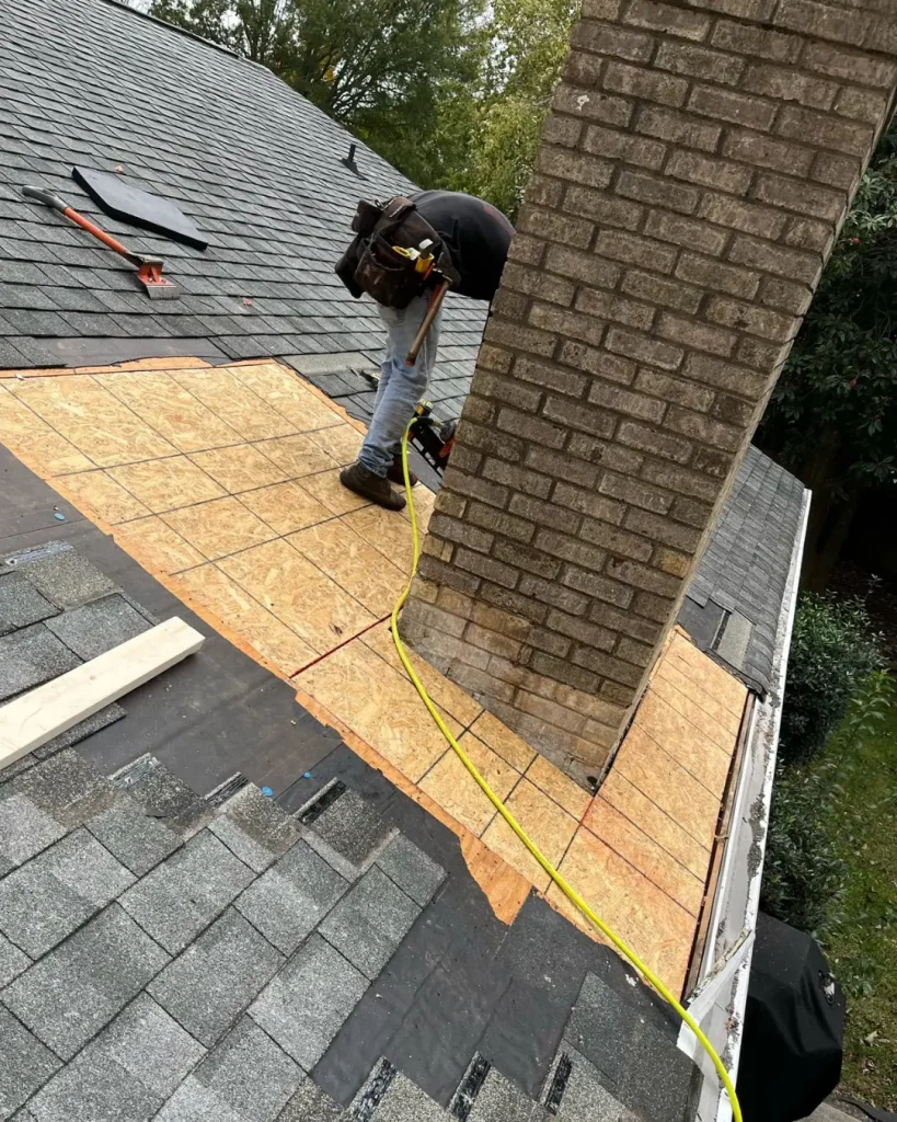 chimney flashing repair in progress showing roof shingles removed and exposed roof deck around brick chimney