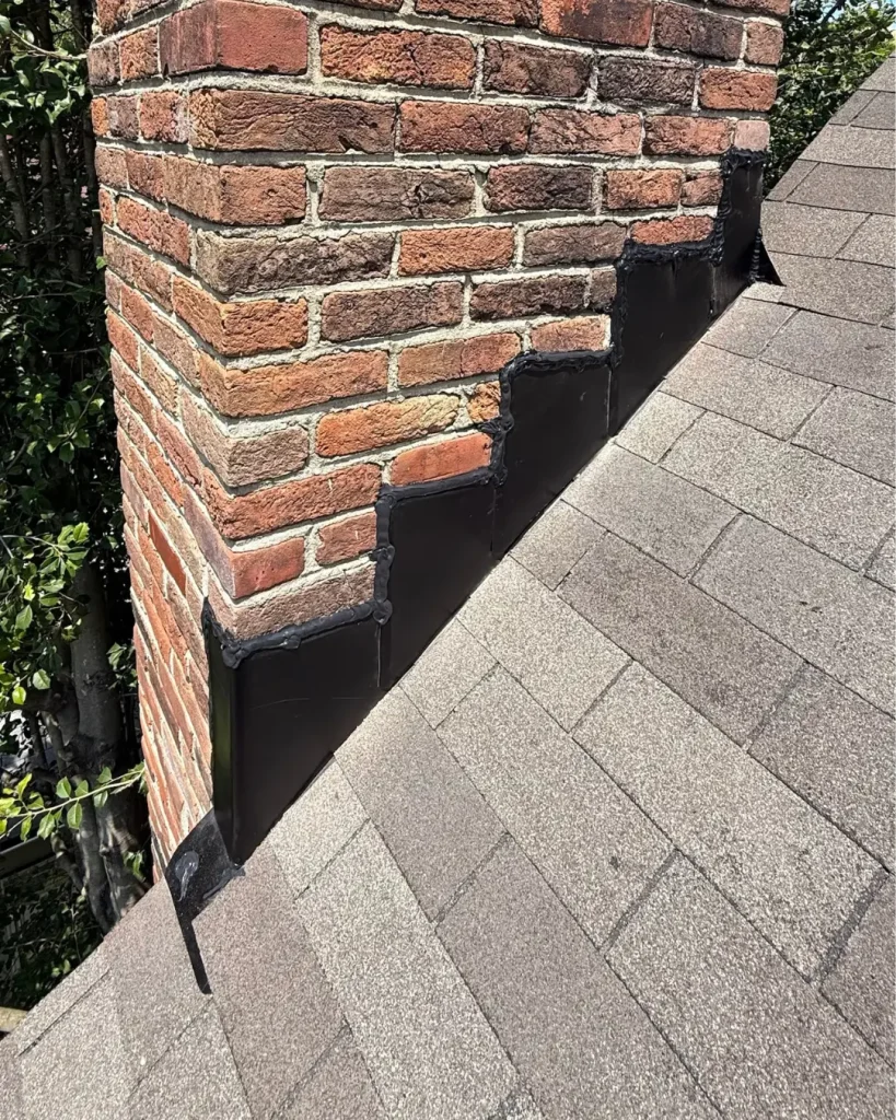 proper step flashing installation along brick chimney roofline showing correctly layered flashing system
