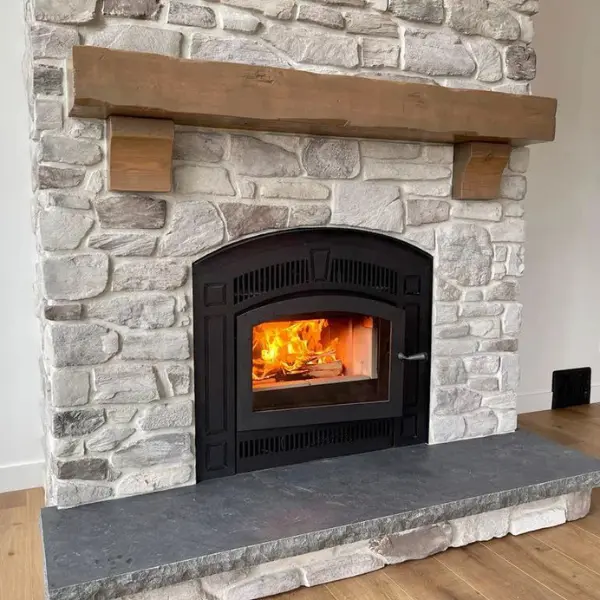 RSF Pearl high-efficiency wood-burning fireplace installed with custom stone veneer surround, mantel, and hearth.