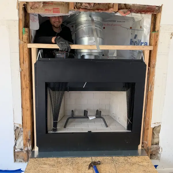 Technician installing a wood burning prefab fireplace in Virginia Beach VA during fireplace replacement project